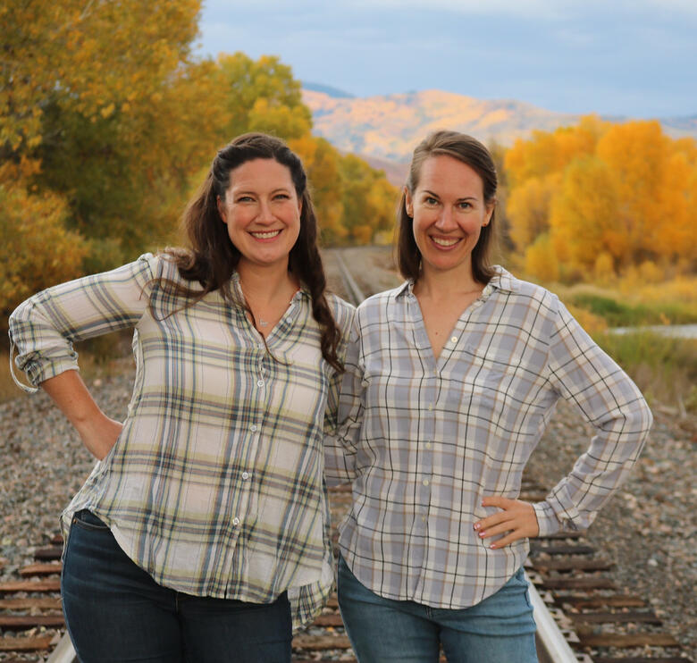 Kelly and Jenny stand in front of Mt. Werner, Steamboat's ski resort, in flannel shirts.